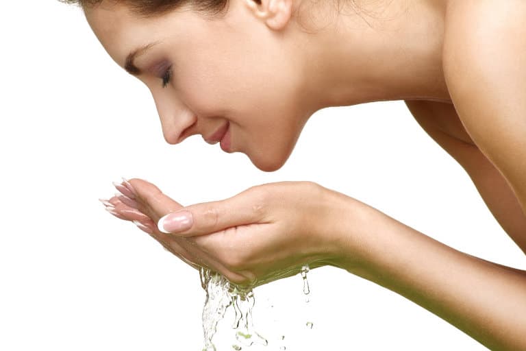 woman refreshing face with handful of water